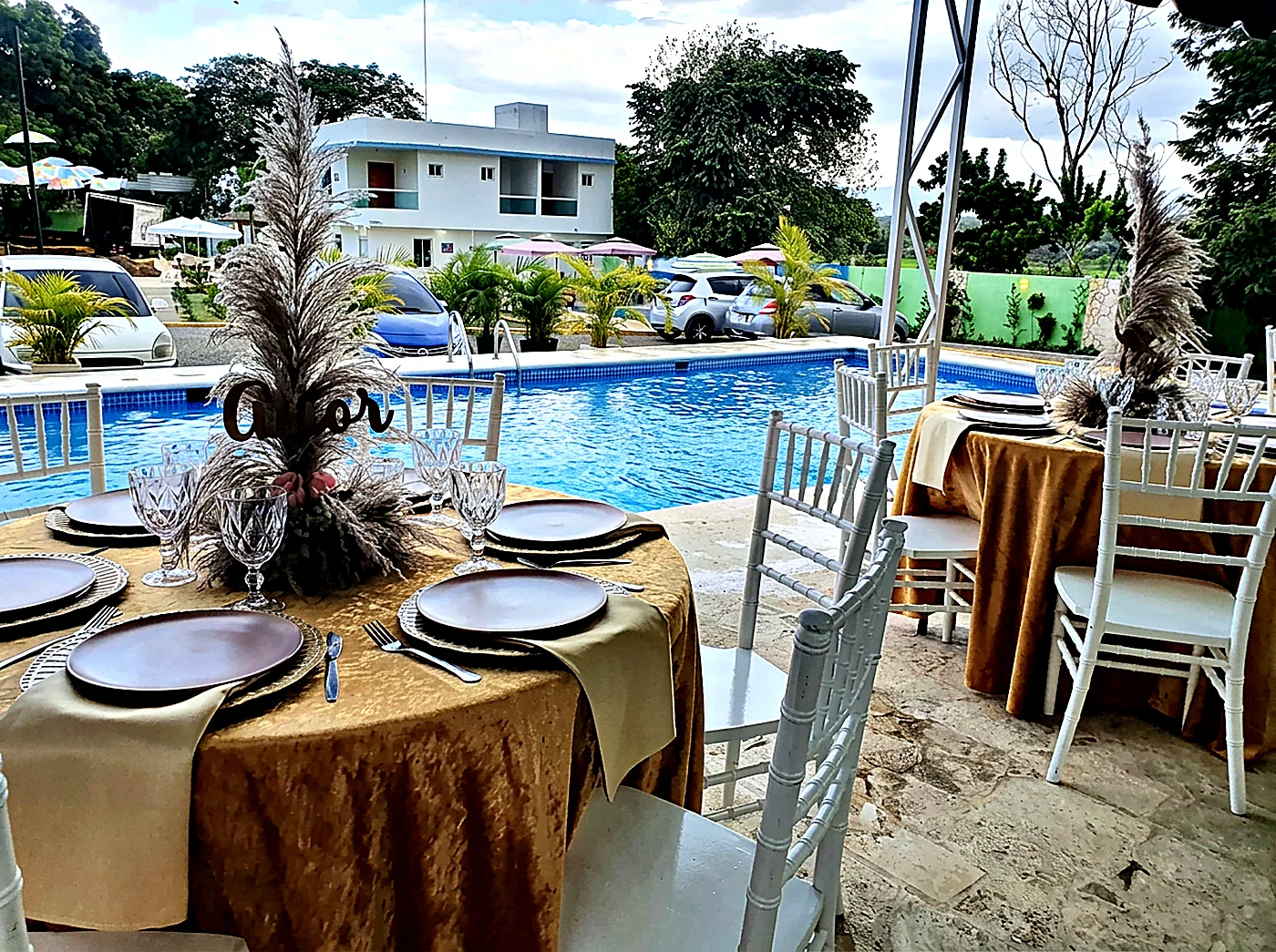 Montaje junto a la piscina con mesa dorada y pampas